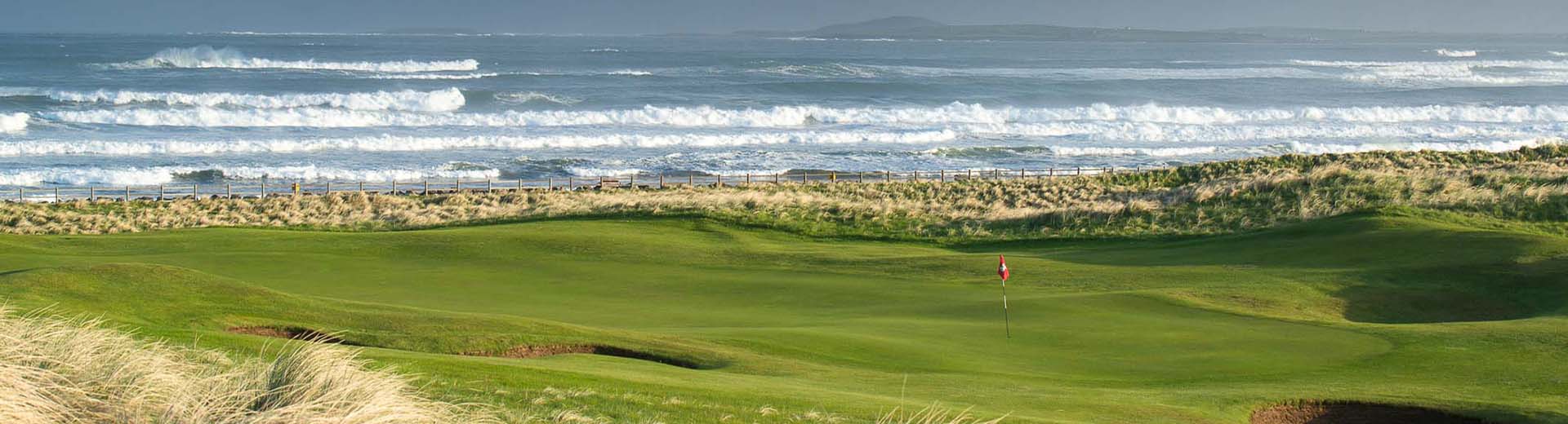 Golf course green with flag off the coast